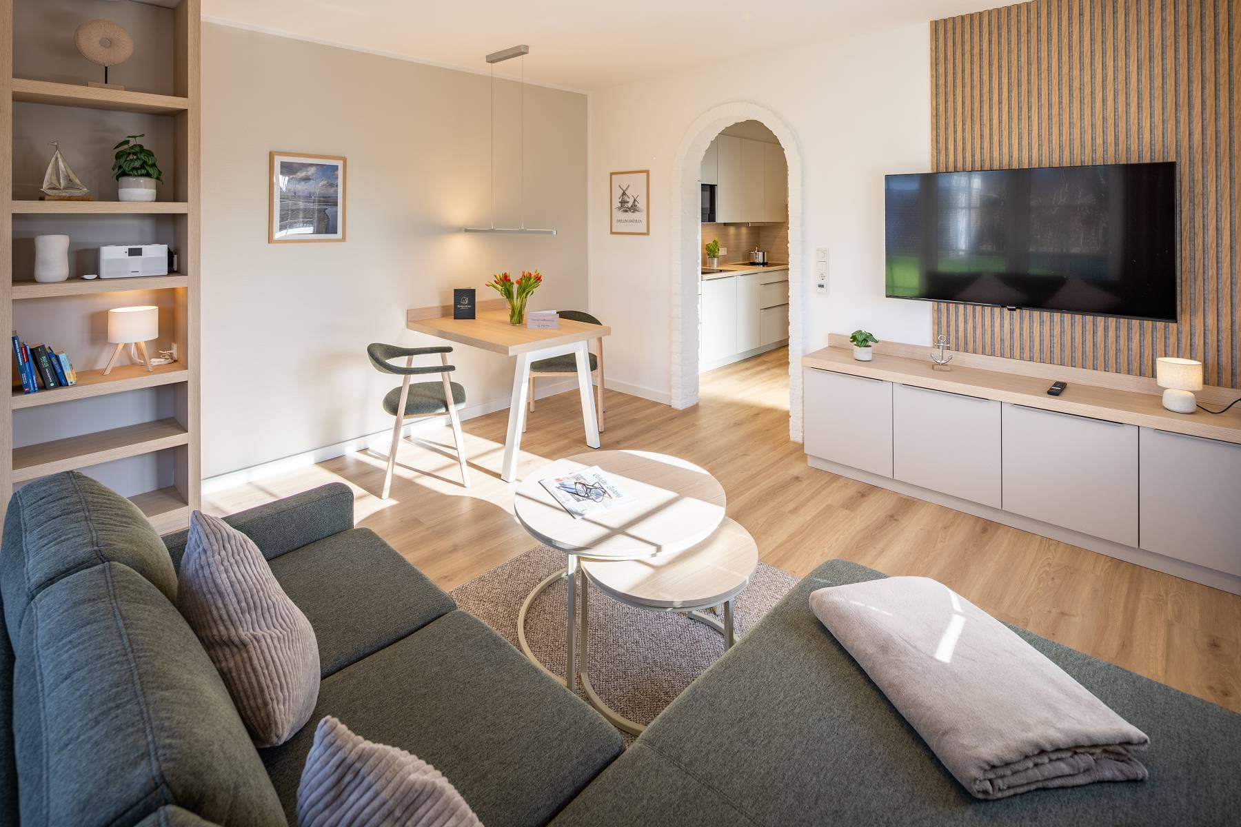 Ferienwohnung Riedgras 1 – Wohnbereich mit Sofa, Couchtisch, Esstisch und Smart-TV