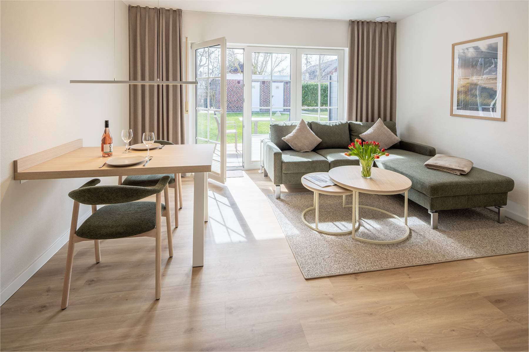 Ferienwohnung Riedgras 2 – Wohnbereich mit Esstisch, Sofa und Terrassentür
