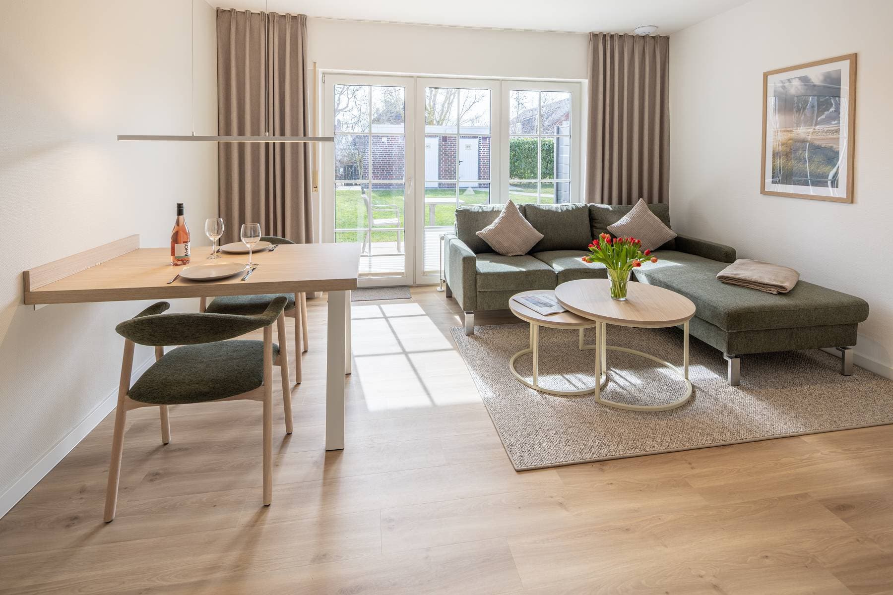 Ferienwohnung Riedgras 2 – Wohnbereich mit Esstisch, Sofa und Terrassentür