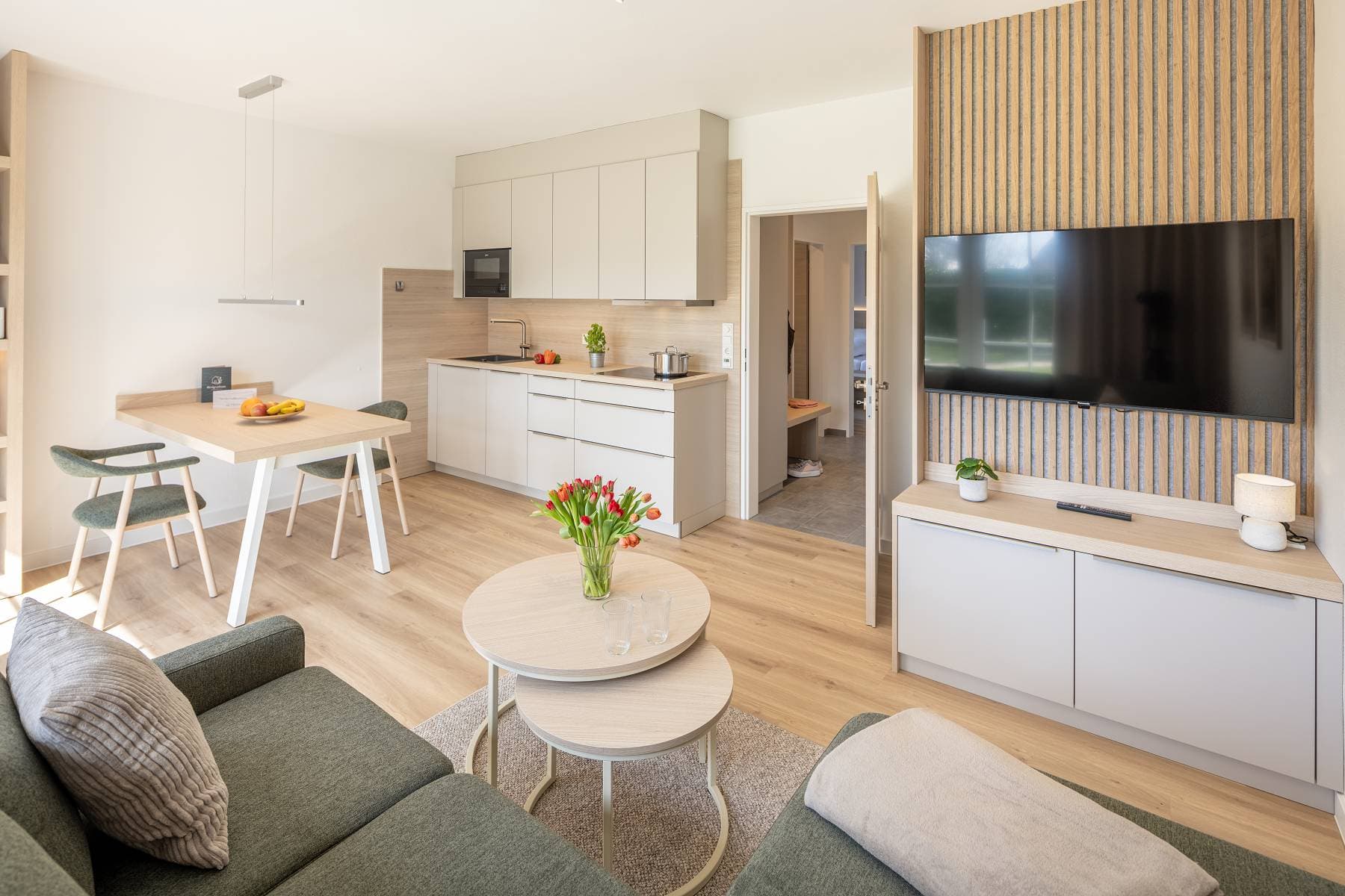 Ferienwohnung Riedgras 3 – Wohnbereich mit Küchenzeile, Esstisch und Smart-TV