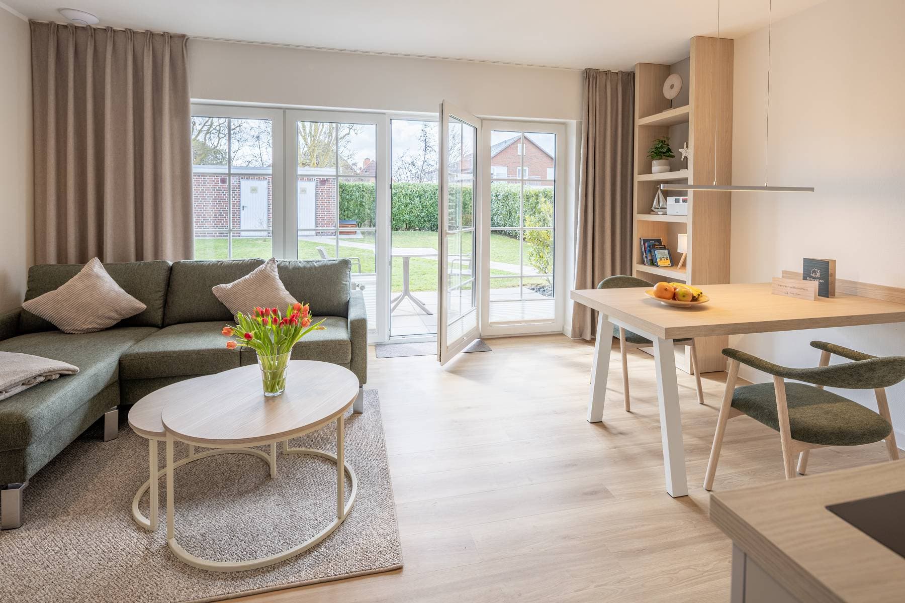 Ferienwohnung Riedgras 3 – Wohnbereich mit Sofa, Esstisch und Terrassentür