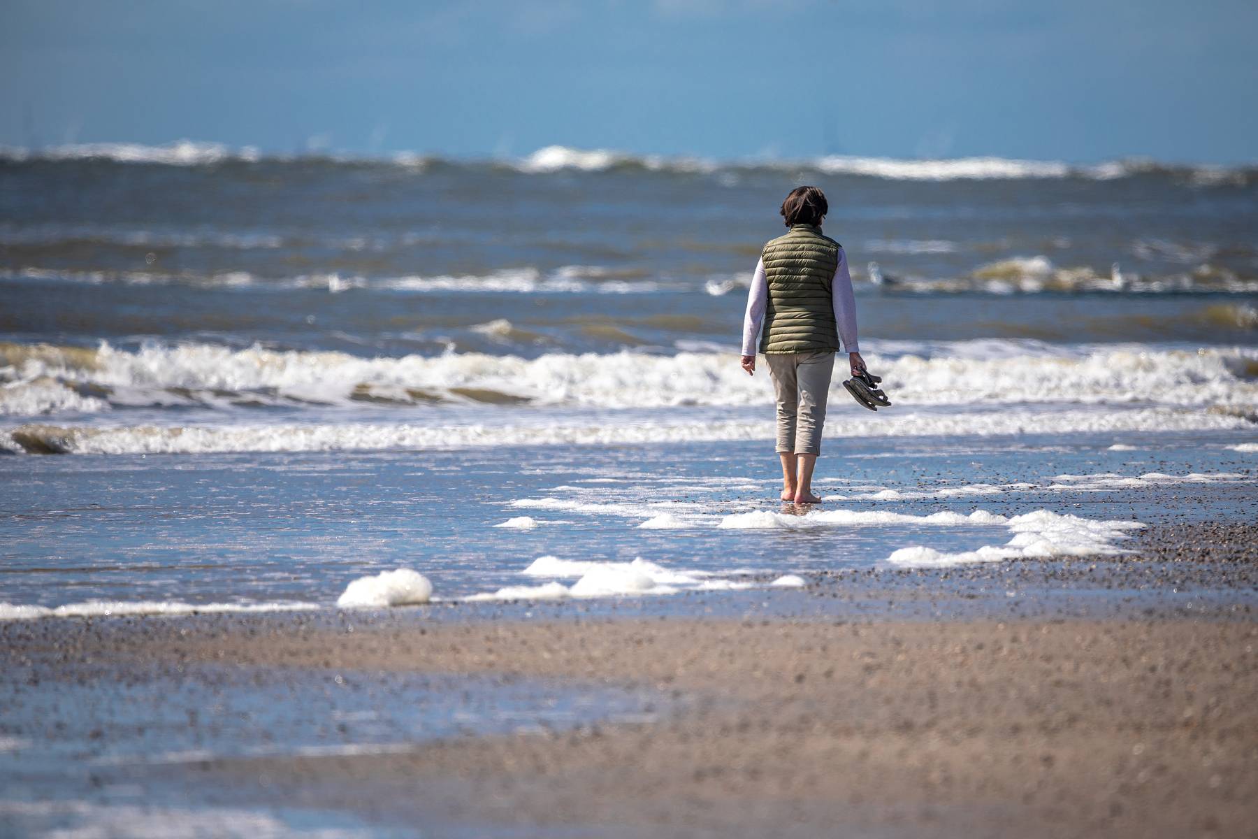 Frau spaziert allein am Meer an der Nordsee